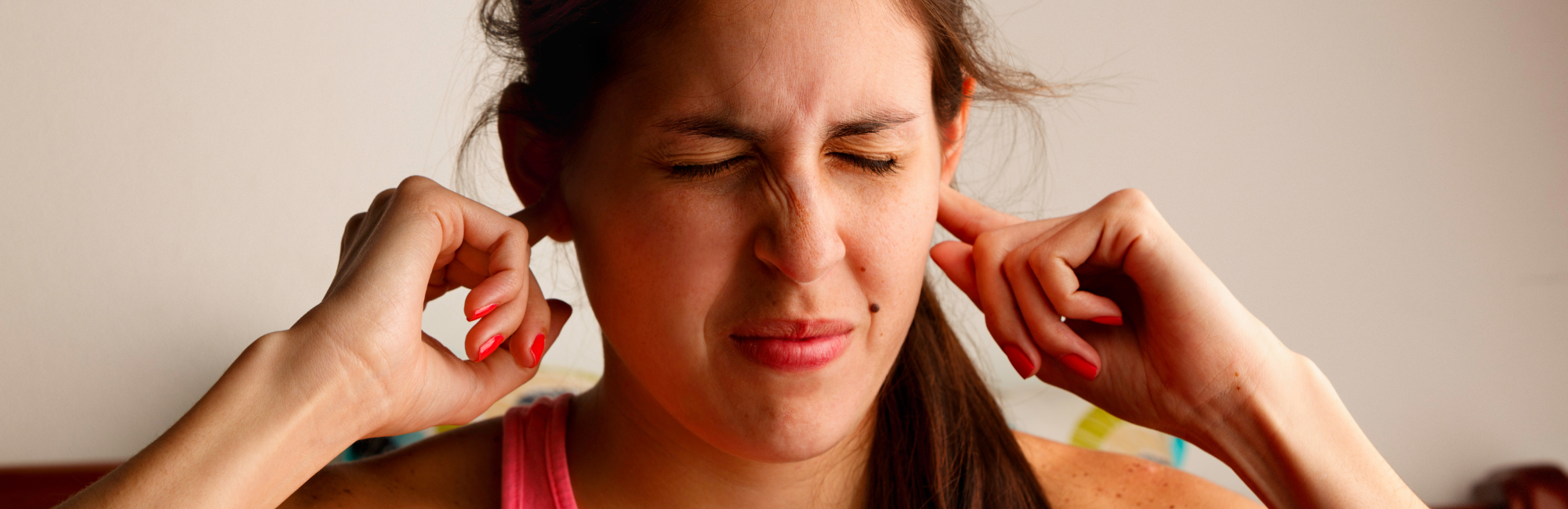 Frau hält sich die Ohren zu